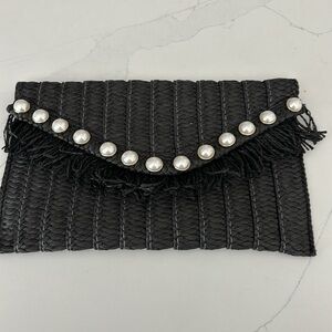 Black straw clutch embellished with pearls.